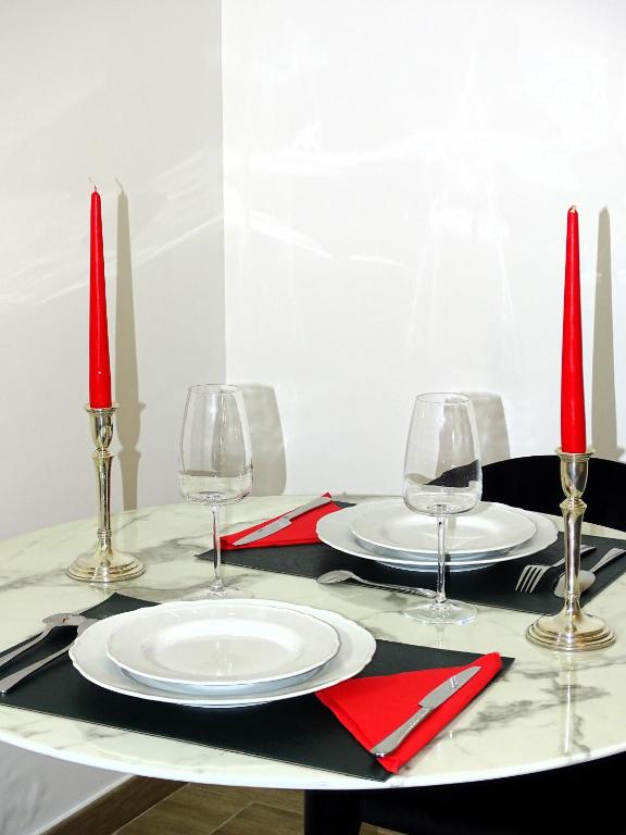 une table avec des bougies rouges, des assiettes et des verres dessus dans l'établissement TILIA JOURDAN-Studio Cosy Aix Centre-Cours MIRABEAU-PARKING-WIFI-SMART TV-RUE CALME, à Aix-en-Provence