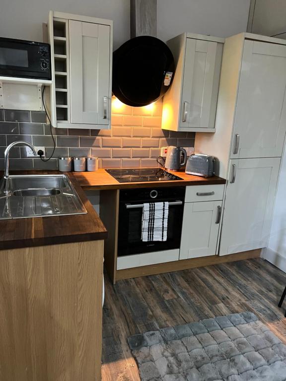 a kitchen with white cabinets and a sink at Stonebarn Lane One Bed in Halton