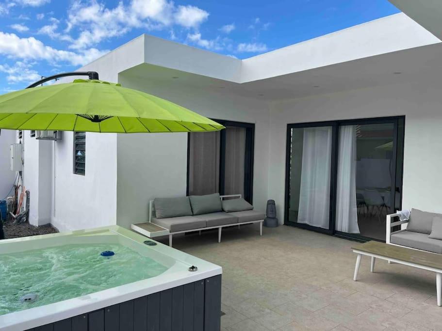 a hot tub with a green umbrella on a patio at Entre ciel et mer in Grand-Baie
