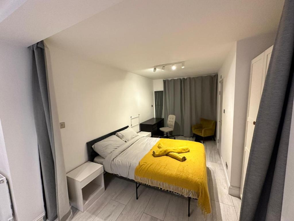 a bedroom with a bed with a yellow blanket on it at The Perfect Spot in Alpha Grove in London