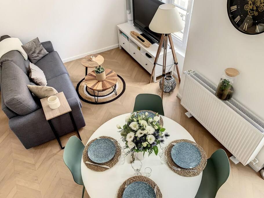 uma sala de estar com uma mesa branca e cadeiras em L'Hippolyte - Cœur de ville em Compiègne