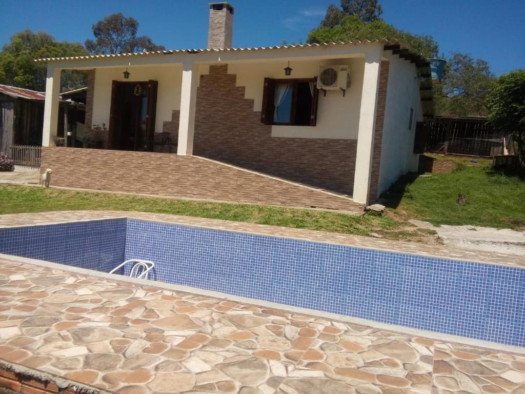 a villa with a swimming pool in front of a house at Casa refúgio in Santana do Livramento