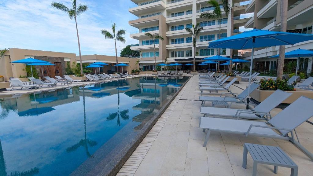 une piscine avec des chaises et des parasols et un hôtel dans l'établissement V Golf, à Puerto Vallarta