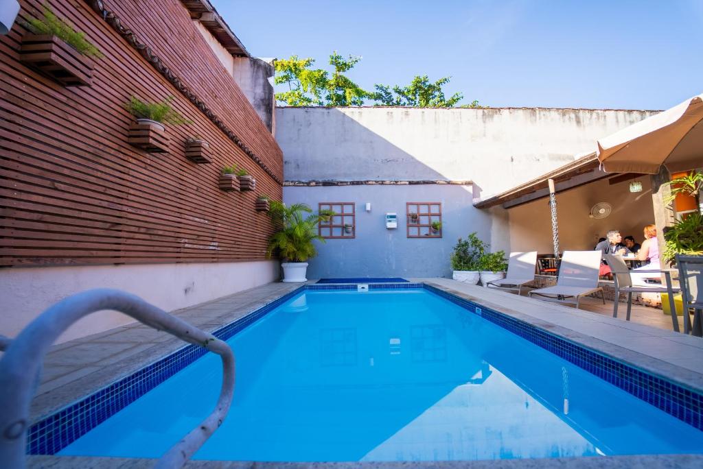 a swimming pool next to a brick wall and a building at Pousada da Praia in Paraty