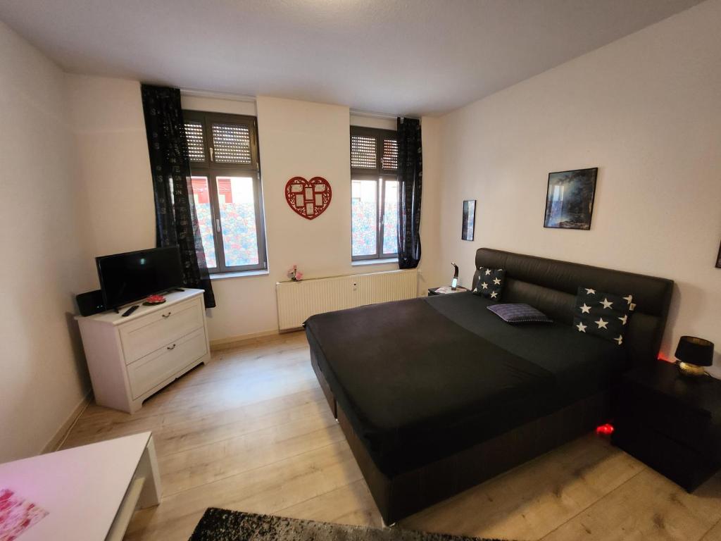 a bedroom with a black bed and a tv at MD- Bukau Günstige 1 oder 2 e c h t e Schlafzimmer mit extra Küche u Bad für relax und verliebte von 18 bis 99 Jahre in Magdeburg