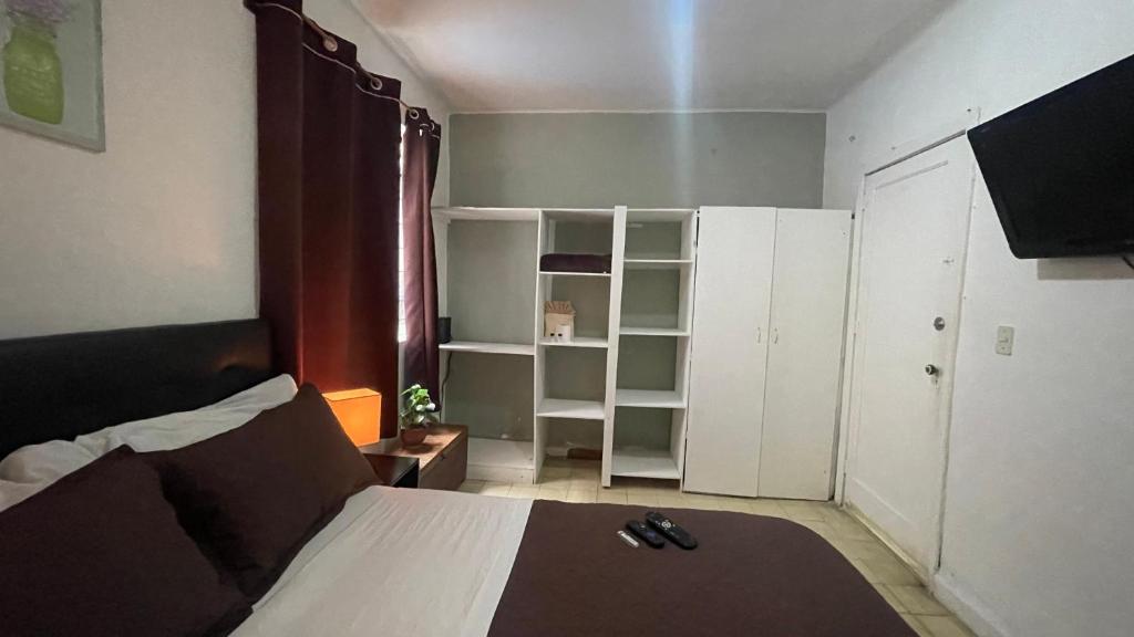 een kleine slaapkamer met een bed en witte kasten bij Bonita y amplia habitación cerca del WTC in Mexico-Stad