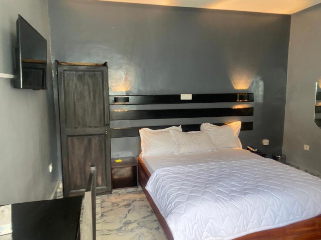 a bedroom with a white bed and a wooden headboard at Sunrise Center Bonapriso - 102 in Douala