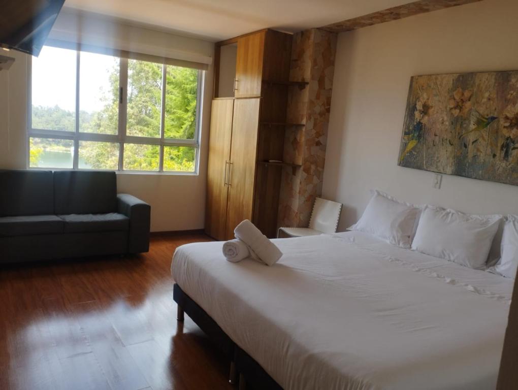 1 dormitorio con 1 cama blanca grande y 1 sofá en Hotel Loma Encantada, Guatapé - Piedra del Peñol, en Guatapé