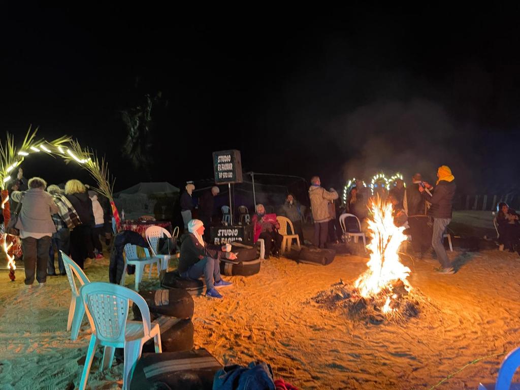 a group of people sitting around a fire on the beach at Luxury Camp Dunes Insolites Sabria in Sabria