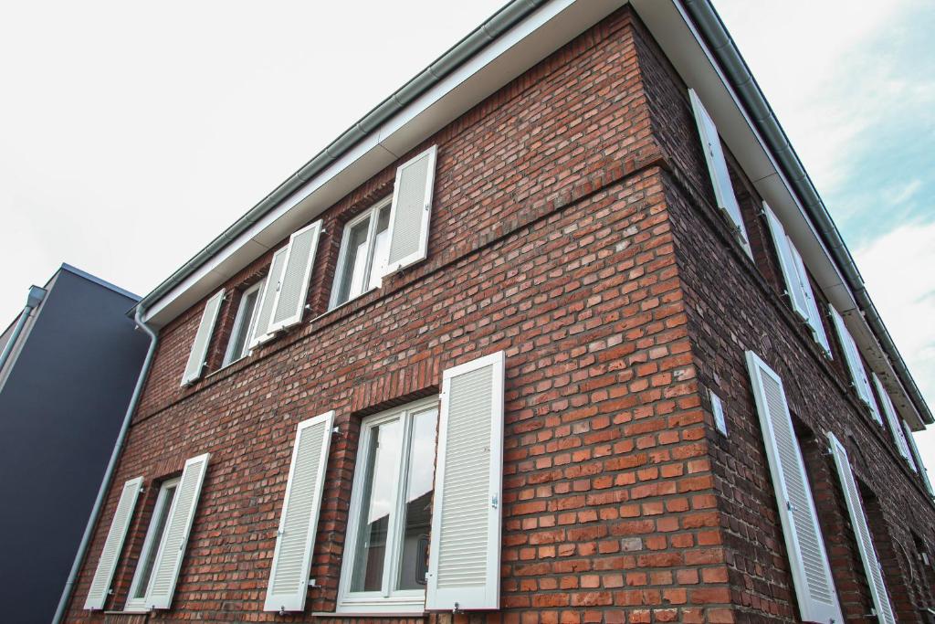 a red brick building with white shutters on it at Green46 in Meerbusch