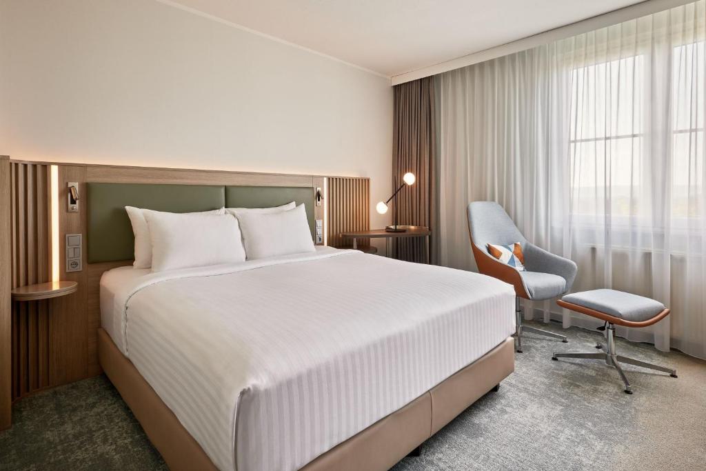ein Hotelzimmer mit einem großen Bett und einem Stuhl in der Unterkunft Courtyard by Marriott Dortmund in Dortmund