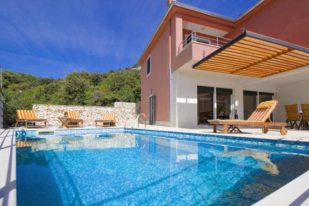 a swimming pool in front of a house at Villa Kamelicina in Vinišće