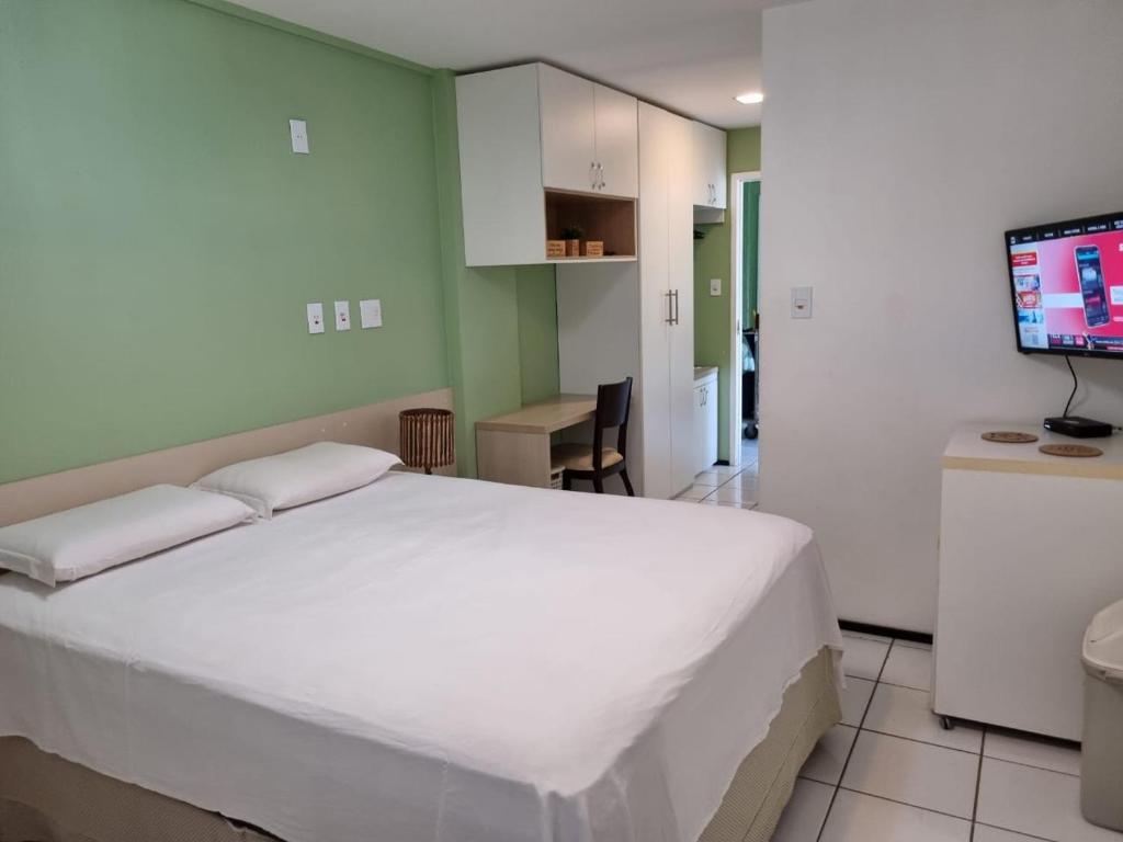 1 dormitorio con 1 cama blanca grande y TV en Gran Lençóis Flat Residence, en Barreirinhas