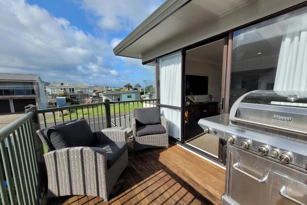 eine Terrasse mit 2 Stühlen und einem Grill auf dem Balkon in der Unterkunft Hosts on the Coast Whiti Te Ra Sunrise in Whitianga
