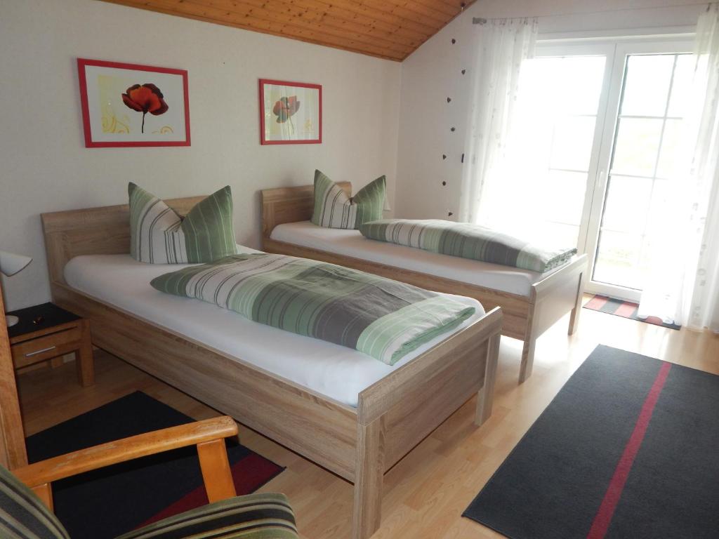 twee bedden in een kamer met twee ramen bij Chefs Gästezimmer in Neupotz