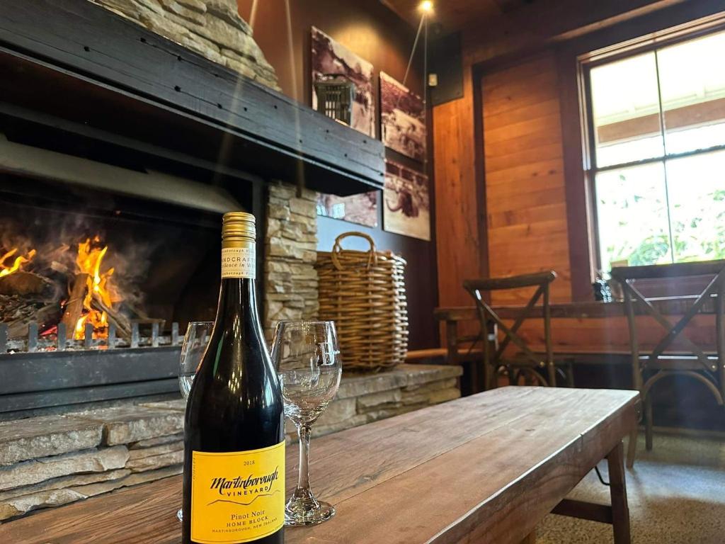 a bottle of wine sitting on a wooden table with wine glasses at Bridgehouse Lodge in Warkworth