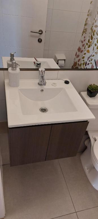 a bathroom with a white sink and a toilet at Hermoso departamento in Iquique