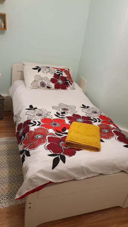 Una cama con una manta y una toalla amarilla. en Private Room Guest Sleep en Londres