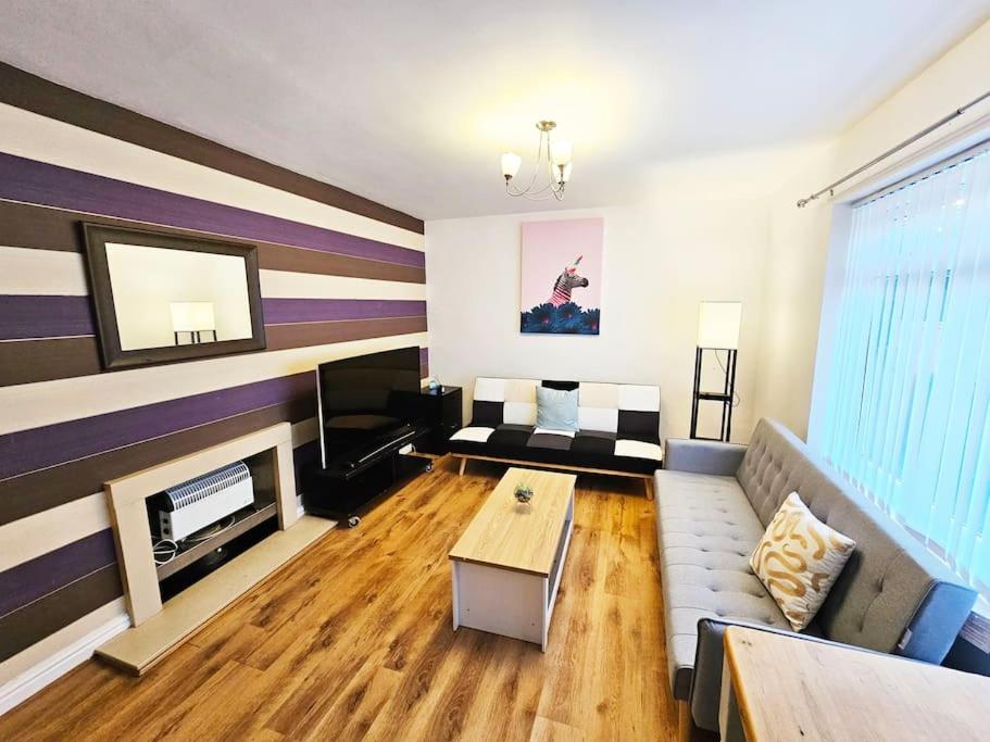 a living room with a couch and a fireplace at Moston, Manchester in Manchester