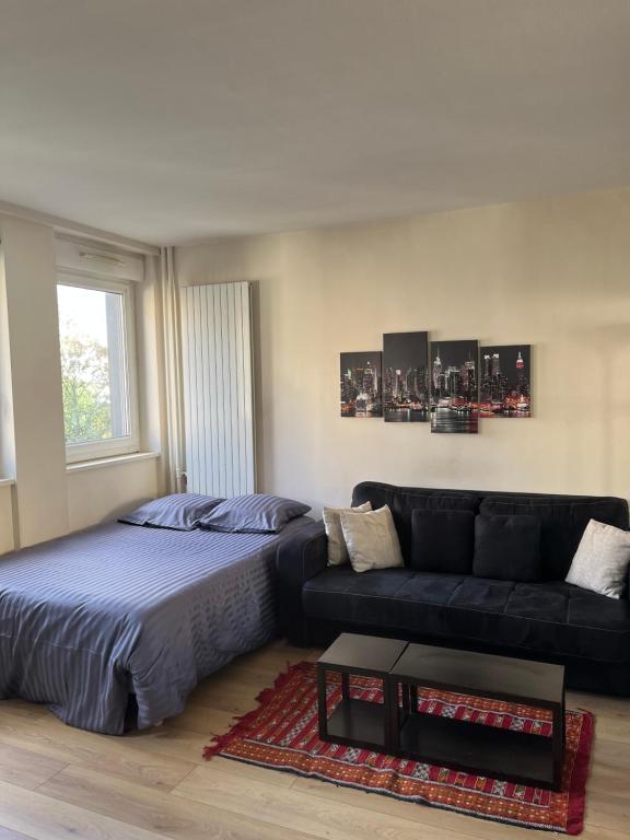 a living room with a bed and a couch at Chic studio Courbevoie Paris in Courbevoie