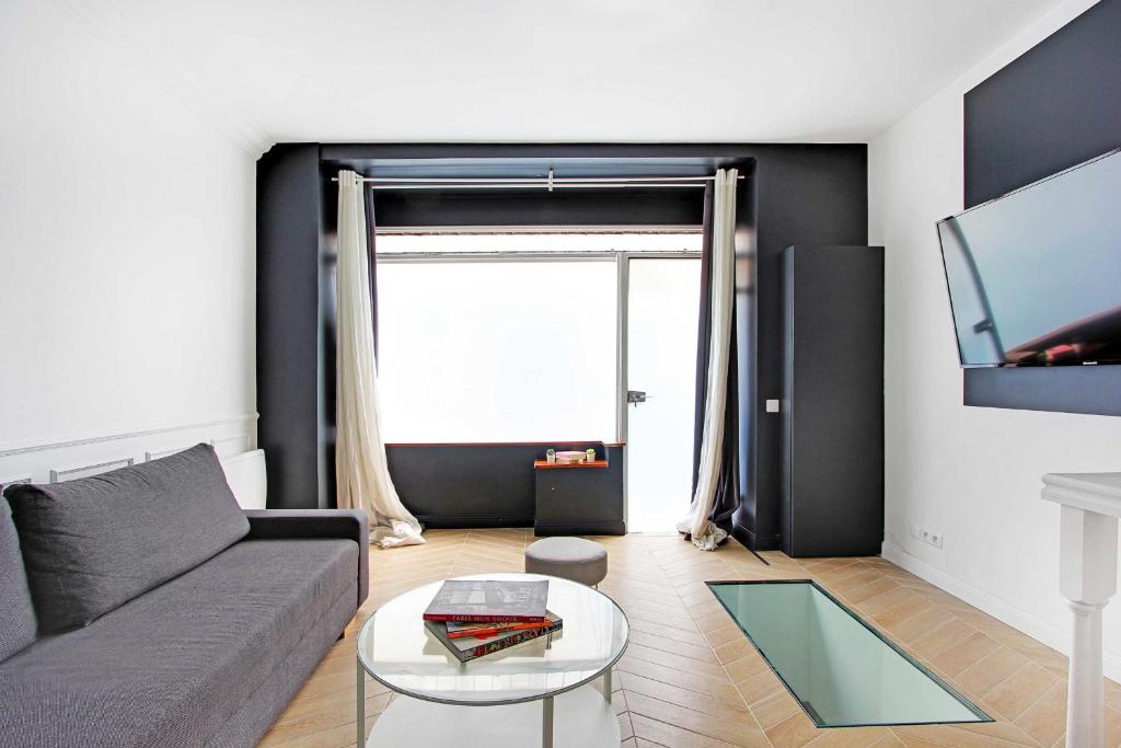 ein Wohnzimmer mit einem Sofa und einem TV in der Unterkunft Modern flexible apt- 1BR2P - Place de la Bastille in Paris