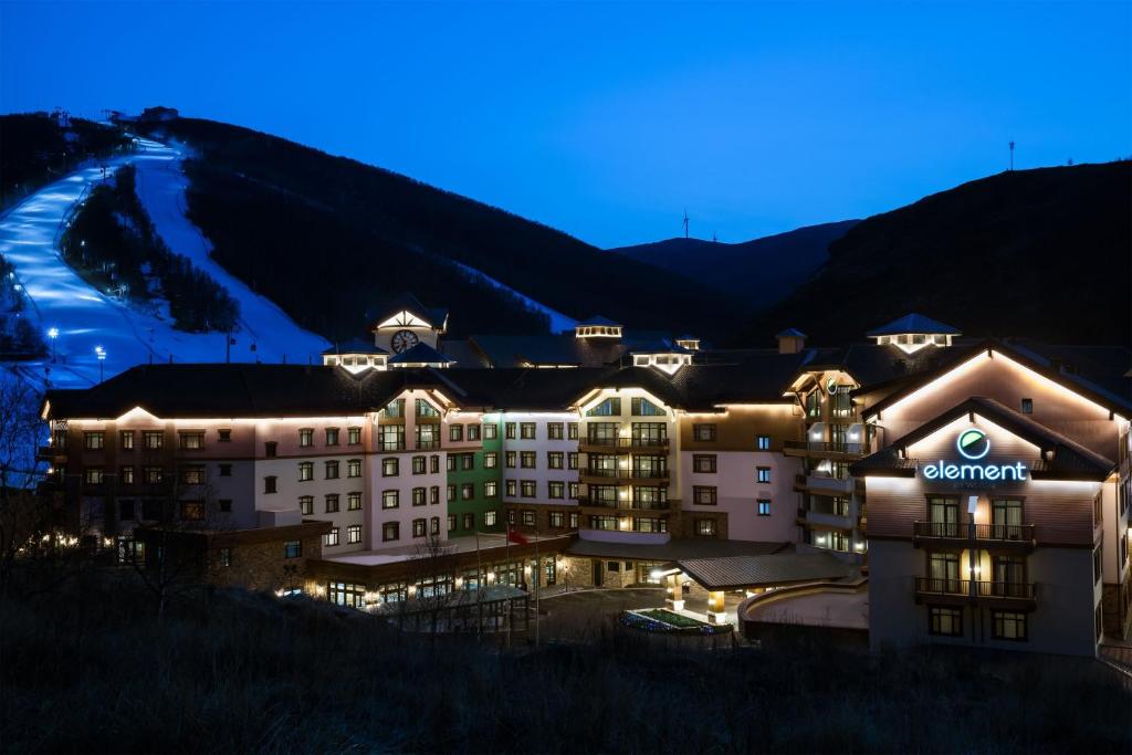 a hotel at night with a mountain in the background at Element Chongli in Chongli