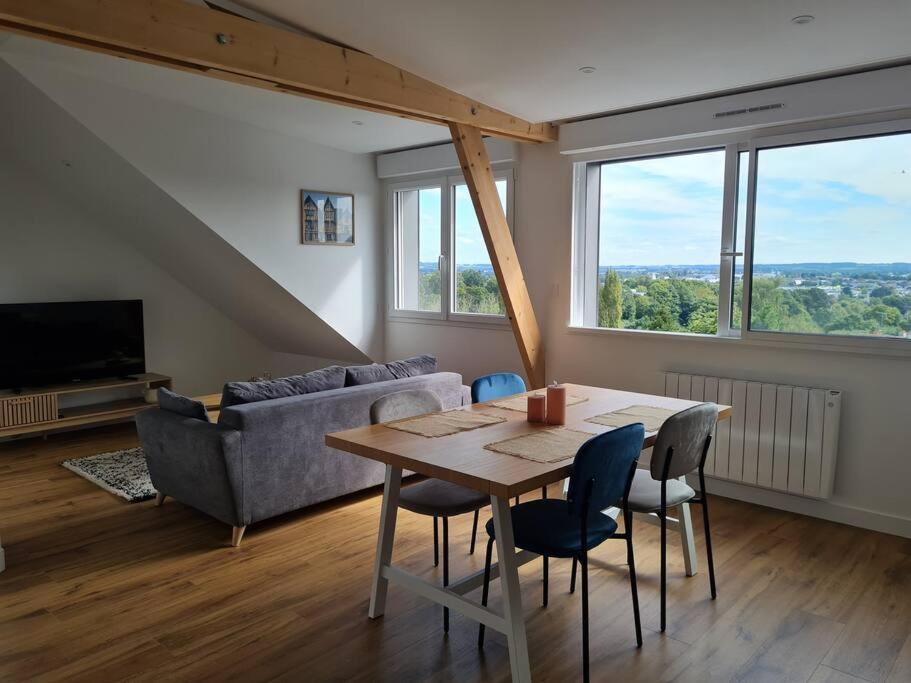 ein Wohnzimmer mit einem Tisch und einem Sofa in der Unterkunft Appartement avec vue in Fougères