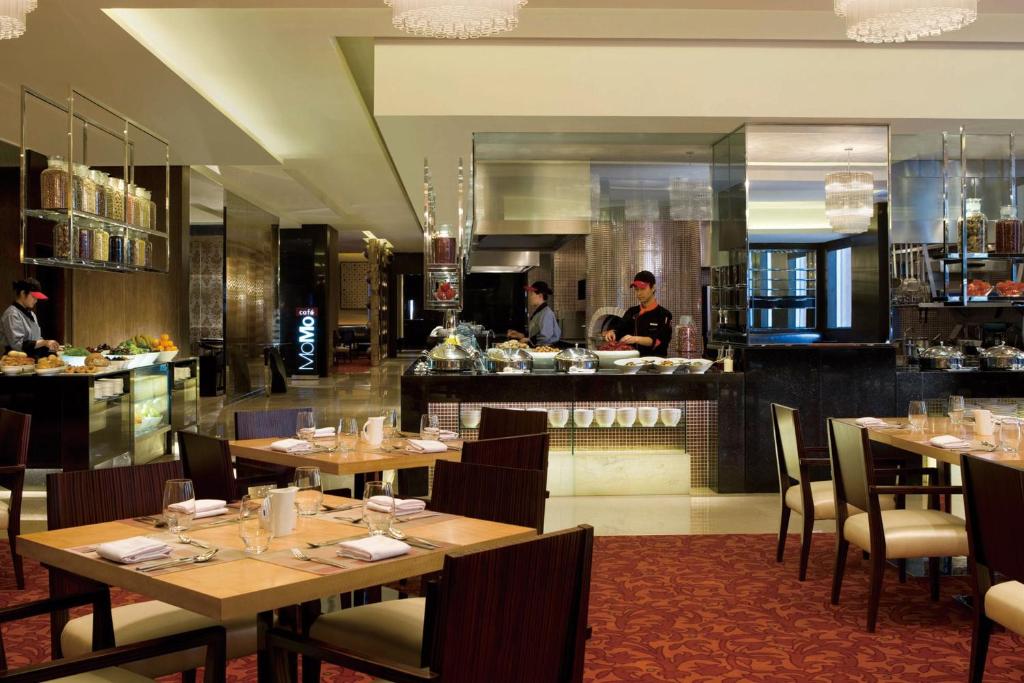 a restaurant with wooden tables and a chef in the kitchen at Courtyard By Marriott Shanghai Xujiahui in Shanghai