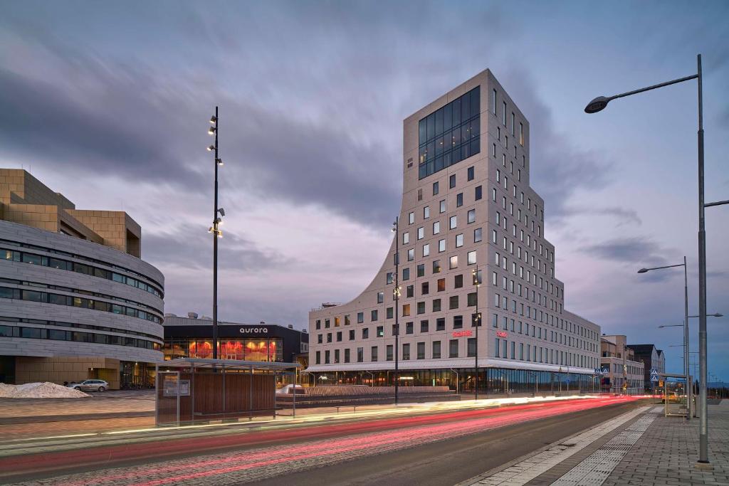 un grand bâtiment blanc dans une rue de la ville avec des bâtiments dans l'établissement Scandic Kiruna, à Kiruna