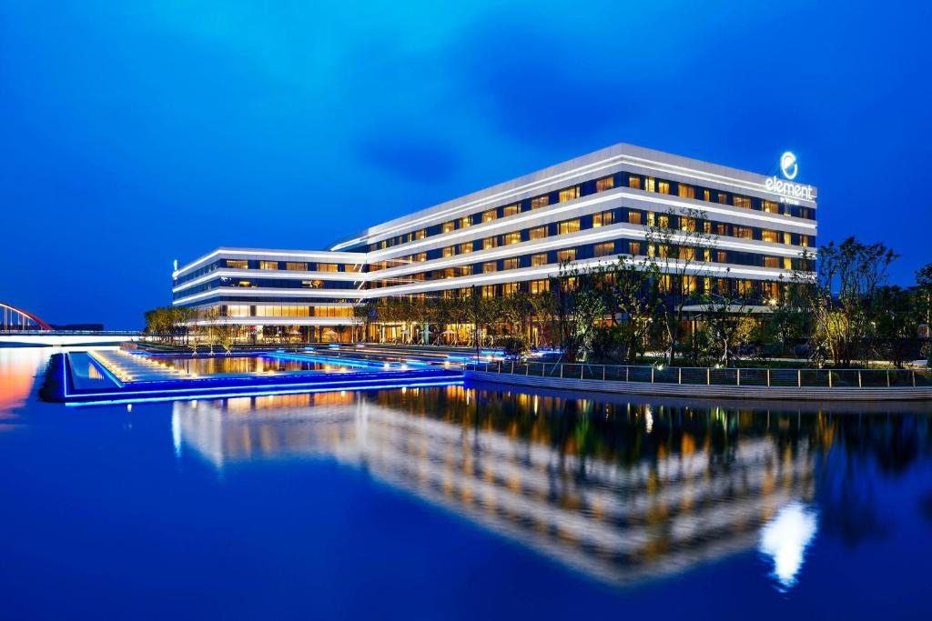 a building with a reflection in the water at night at Element Suzhou Science and Technology Town in Suzhou