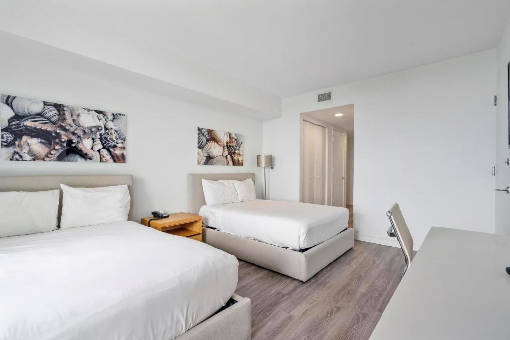 two beds in a room with white walls and wooden floors at Modern Studio rental at Beachwalk Resort Hollywood 18th floor in Hollywood
