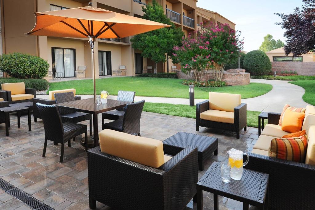 un patio con tavoli, sedie e ombrellone di Courtyard by Marriott Oklahoma City Airport a Oklahoma City