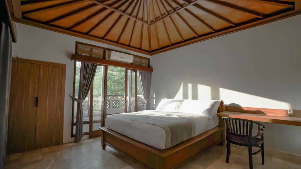 a bedroom with a bed and a desk and window at New Mumbul Ubud in Ubud