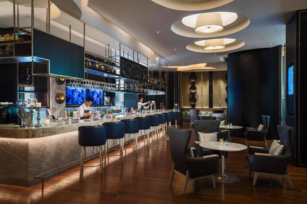 a restaurant with a bar with blue chairs and tables at Renaissance Suzhou Hotel in Suzhou