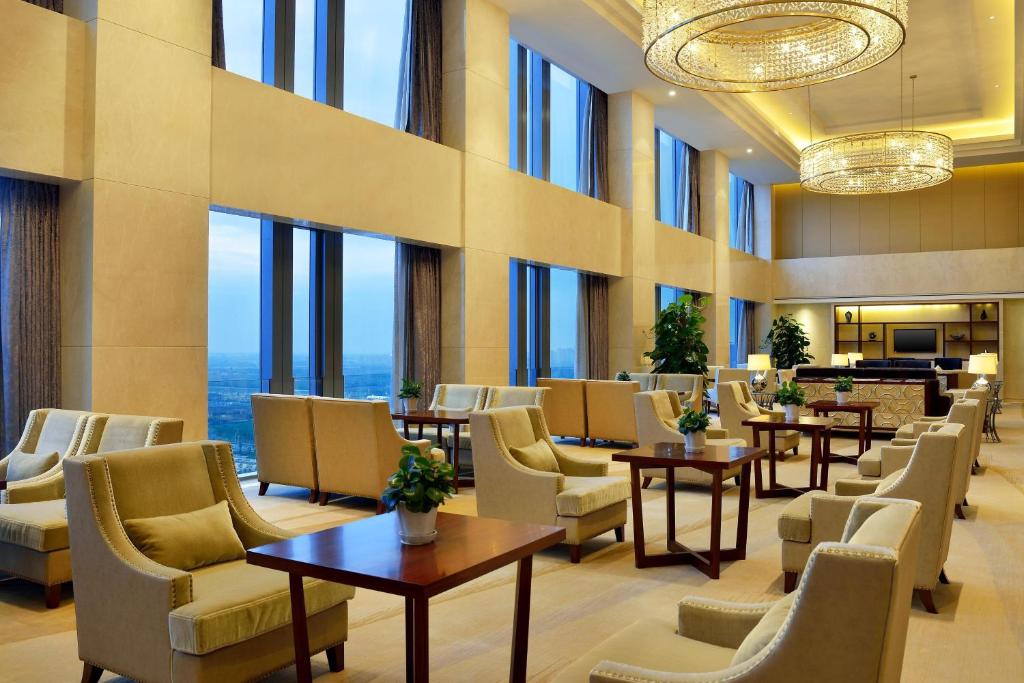 un vestíbulo del hotel con mesas, sillas y ventanas en Sheraton Shenyang South City Hotel en Shenyang