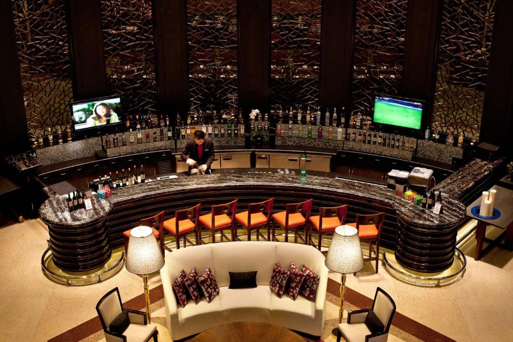 a man sitting at a bar in a building at Courtyard By Marriott Shanghai Pudong in Shanghai