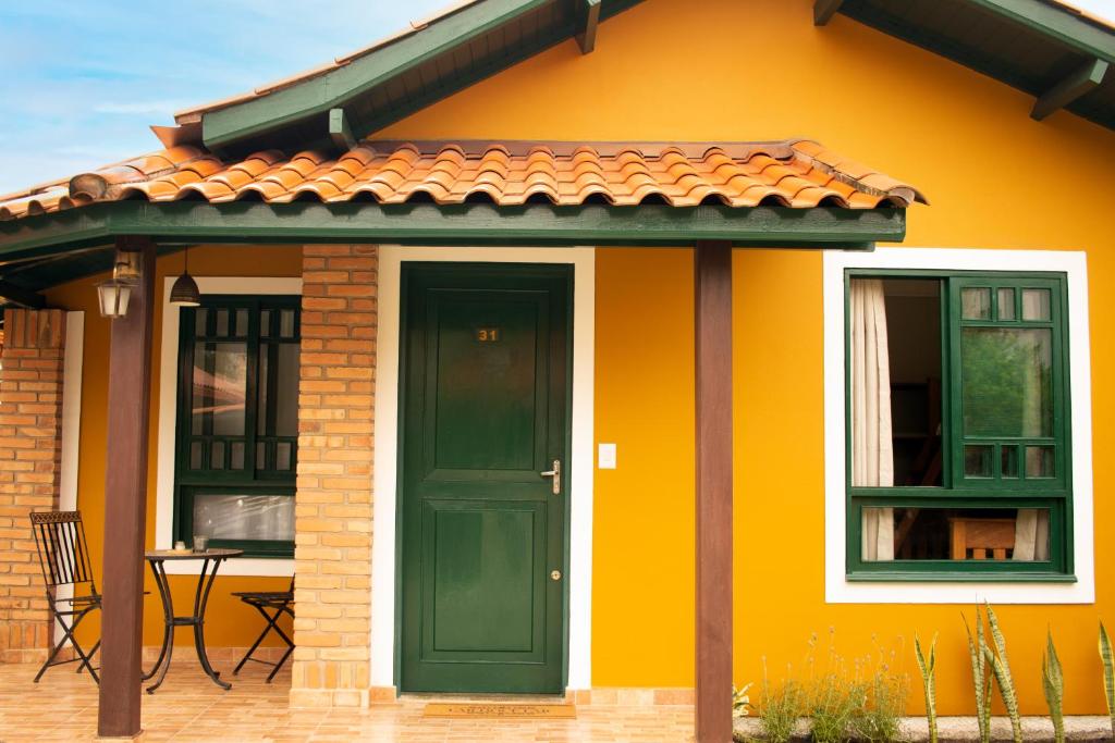 una casa amarilla con una puerta verde y una mesa en Chalé 31 en Florianópolis