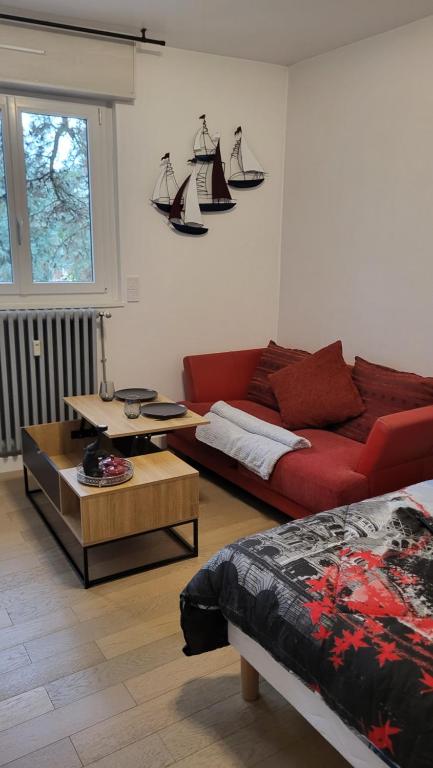 a living room with a red couch and a table at Appartement jolie vue WIFI in Besançon