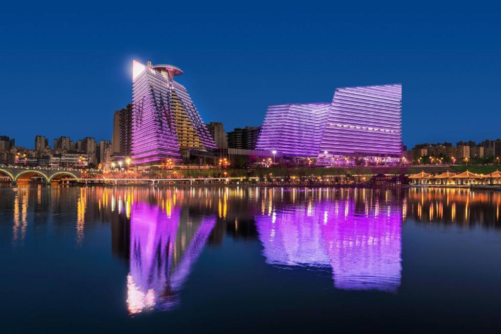 une vue sur la ville la nuit avec des lumières violettes sur l'eau dans l'établissement W XIAN Hotel, à Xi'an