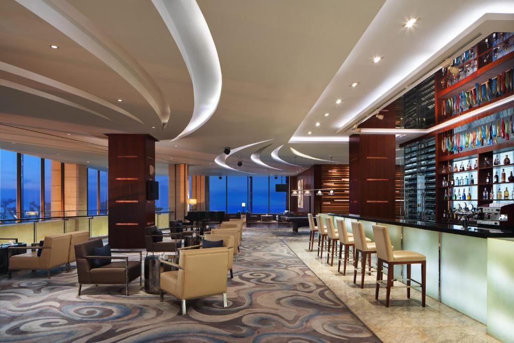 a restaurant with a bar with chairs and tables at Sheraton Yantai Golden Beach Resort in Yantai