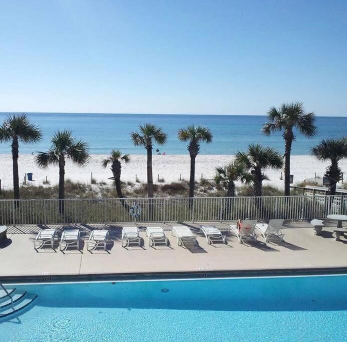 a pool with chairs and palm trees and the beach at Wanderlust Villa only 3 min walk to the Sand! in Panama City Beach