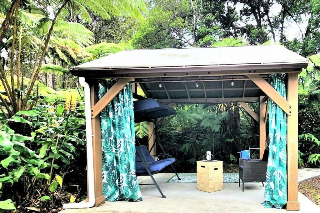 un cenador con cortinas azules y una silla en Romantic Retreat, Pop up Dome at your own private yard, Outdoor shower, firepit, 5 min to Hawaii Volcano park, en Volcano