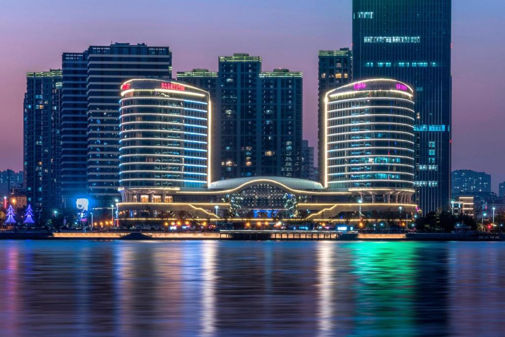 a city skyline at night with the water in front at Sheraton Qingdao West Coast in Huangdao