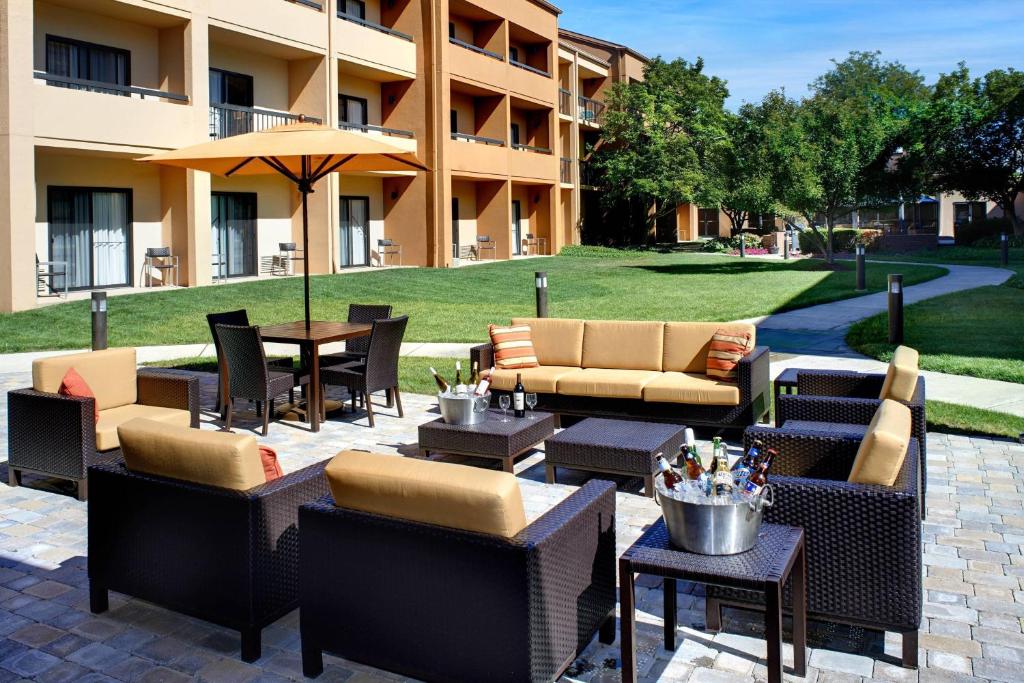 un patio avec des chaises et des tables ainsi qu'un bâtiment dans l'établissement Courtyard Toledo Airport Holland, à Holland