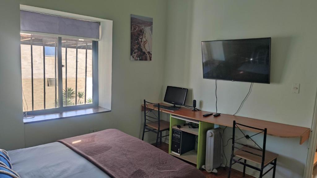 1 dormitorio con 1 cama y escritorio con TV en Departamento Reñaca Quinto Sector en calle Bellavista, en Viña del Mar