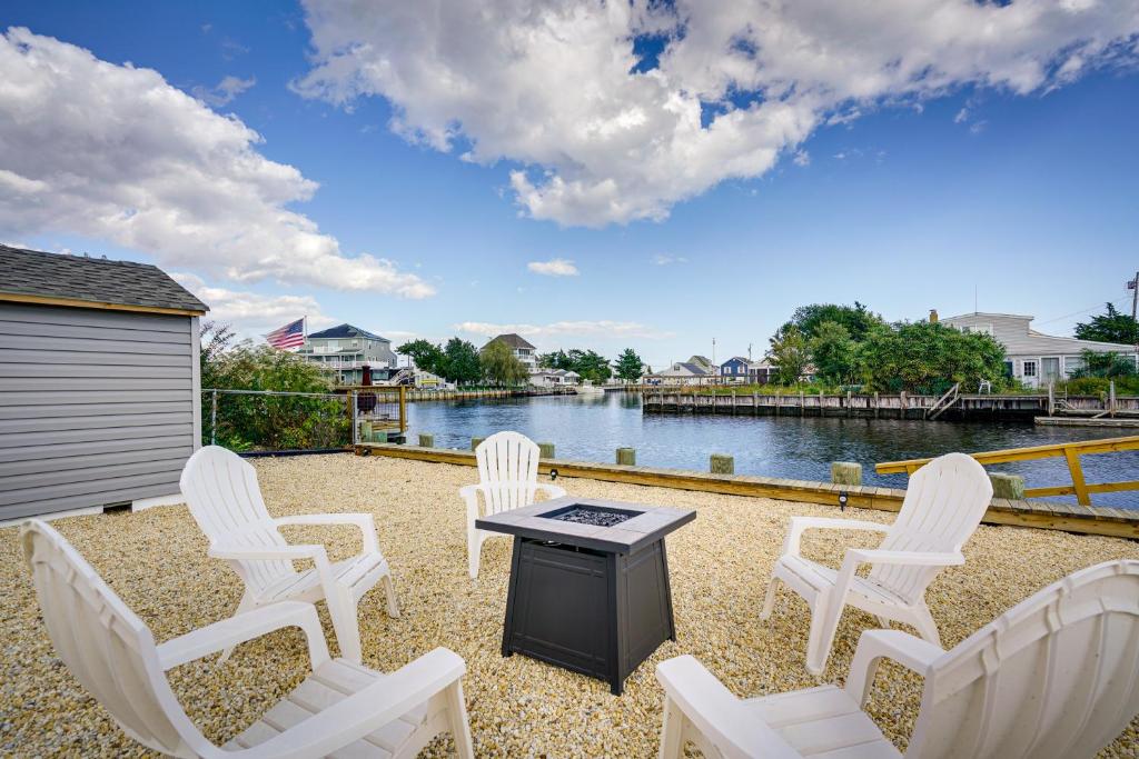 um grupo de cadeiras brancas e uma mesa e água em Waterfront Mystic Island Home with Boat Dock! em Little Egg Harbor Township