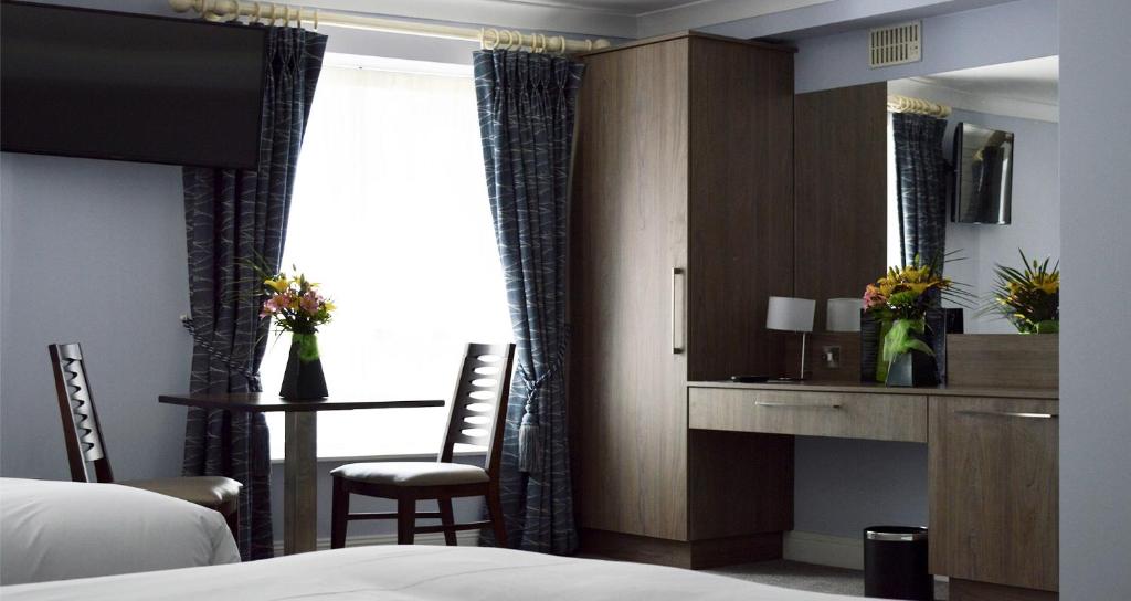 a hotel room with a bed and a desk and a window at Slaney Suites in Enniscorthy