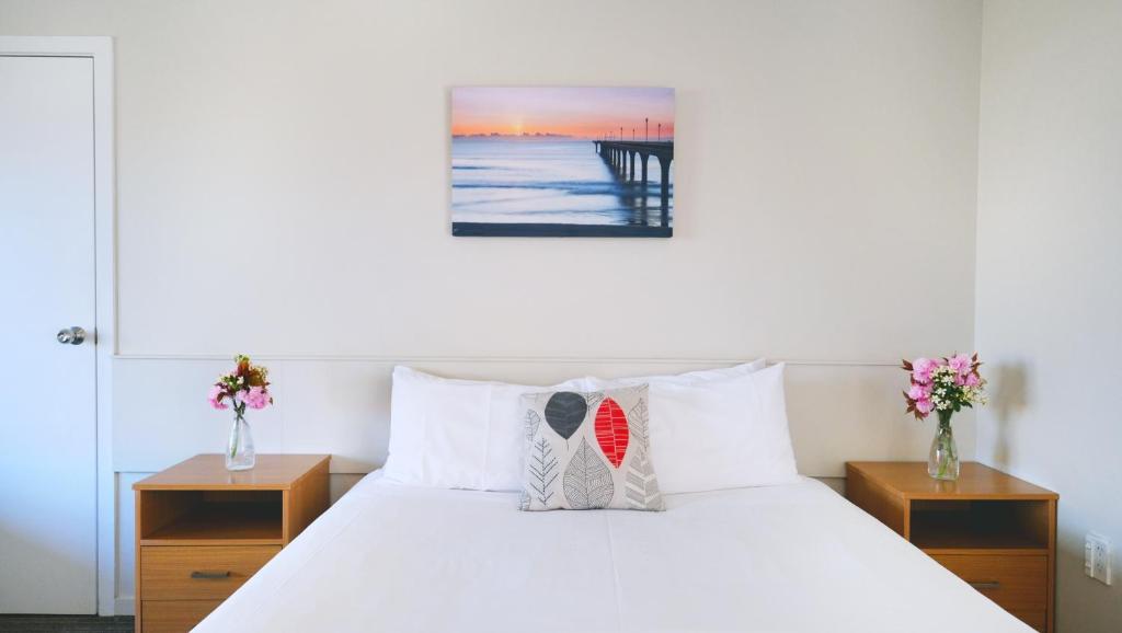 um quarto com uma cama com lençóis brancos e um cais em The Garden Hotel em Christchurch