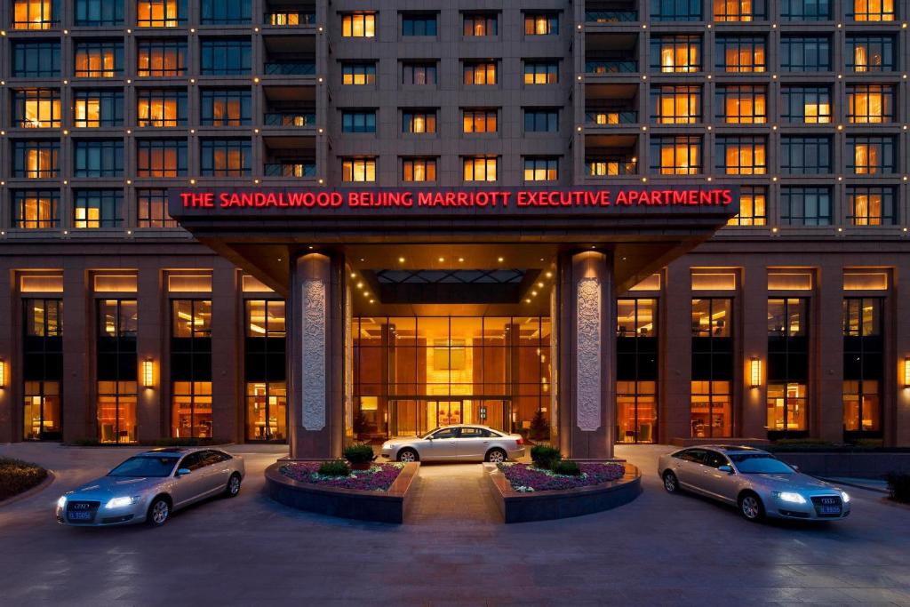 un edificio con tres coches estacionados frente a él en The Sandalwood Beijing Marriott Executive Apartments, en Beijing