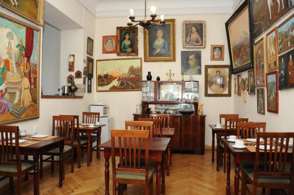 un restaurante con mesas, sillas y cuadros en la pared en Gutsa Artists Mini-Hotel, en Tiflis